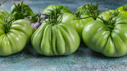 Food banner Green tomatoes close-up on a blue concrete background