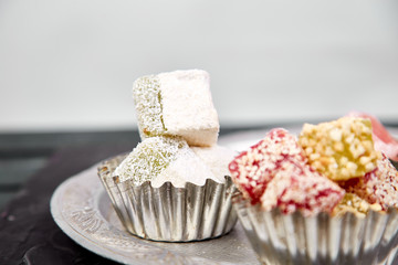 Set of various Turkish delight in traditional silver bowl on metal tray black background.Middle Eastern dessert.