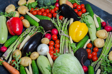 top view portrait of Assortment of fresh raw vegetables on black wooden background.
