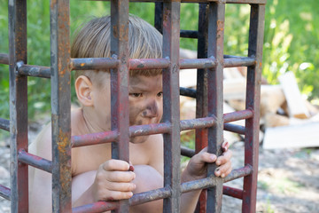 5-year-old white-skinned boy with blond hair stripped and soiled sitting in a cage. .concept...