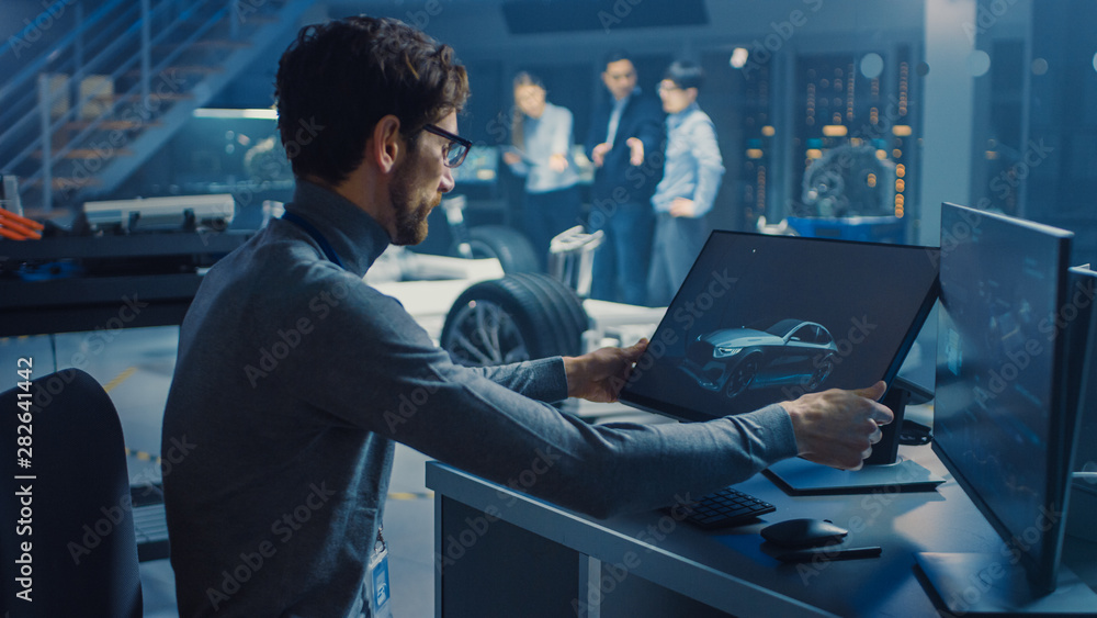 Poster Professional Automotive Graphic Designer is Working on Concept Car Render with a Stylus Pen in a High Tech Innovative Laboratory with a Prototype Car Chassis.