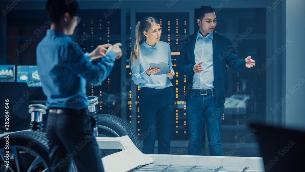 Aufkleber Shot of a Development Laboratory Room with Diverse Professional Team of Engineers and Scientists Working on a Electric Car Chassis with Wheels, Batteries, Engine and Suspension. 