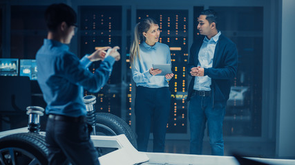 Automotive Design Engineer and Scientist with Tablet Discuss the Electric Car Chassis Prototype. In...