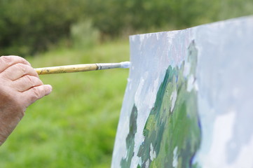 Drawing oil paintings of a natural landscape on a white cardboard