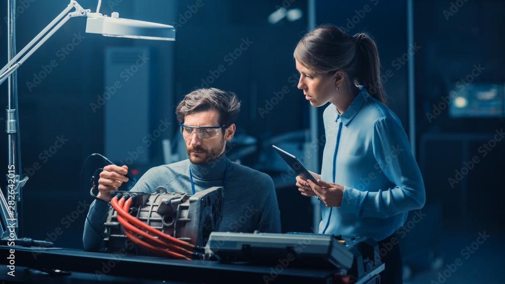 Poster male and female automotive engineers with a tablet computer and inspection tools are having a conver