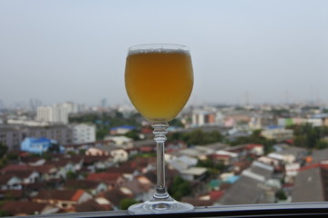 A glass of wine on the balcony on a tall building and clear sky
