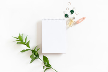 Composition with open spiral notepad, ruscus branch and women's accessories on white background