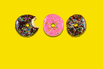 Sweet donuts with icing on yellow background