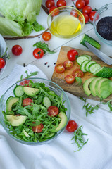 Fresh salad with cucumbers, cherry tomatoes, arugula, avocado, baby corn on white background. Vegetables on wood. Bio Healthy food, herbs and spices. Organic vegetables on wood.