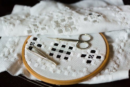 Handmade hemstitch embroidery called Hardanger on wooden hoop, metall scissors and tweezers