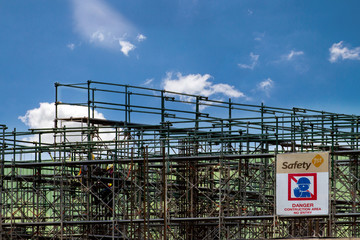 Construction site with scaffold tower and warning label building with blue sky background,scaffolding for construction factory