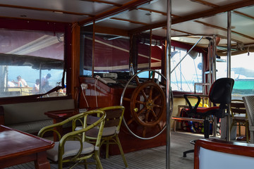 Steering wheel and engine controls on the ship bridge of a pleasure craft.