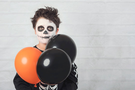 Happy Halloween. Funny Child In A Skeleton Costume With Colorful Balloons.