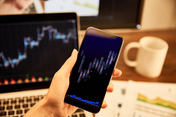 cropped view of man holding smartphone with graphs and charts
