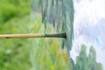 Drawing oil paintings of a natural landscape on a white cardboard