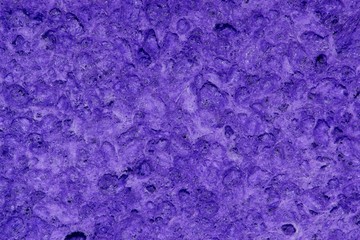 Macro image of a vibrant purple dish washing sponge showing the uneven porous surface with all its textured nooks and crannies.