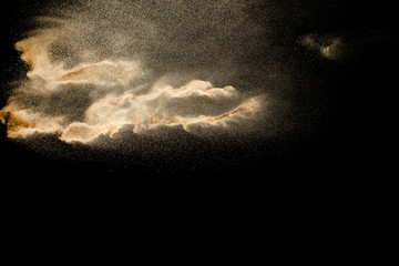 Brown colored sand splash against dark background. Dry river sand explosion isolated on black...