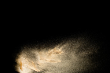 Brown colored sand splash against dark background. Dry river sand explosion isolated on black...
