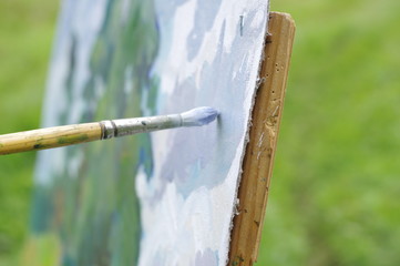 Drawing oil paintings of a natural landscape on a white cardboard
