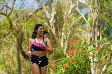 young happy attractive and exotic Asian Indonesian runner woman in jogging workout outdoors at countryside road track nature background running cheerful