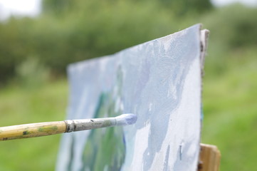 Drawing oil paintings of a natural landscape on a white cardboard