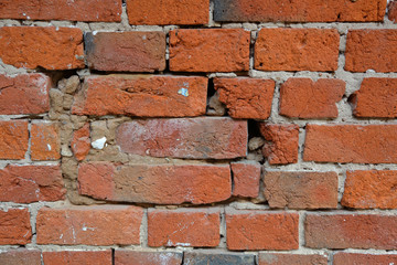Fototapeta premium Embossed textured surface of the old orange brick and cement wall