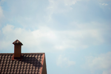 brown roof of a house with a chimney against a blue sky