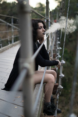 emo goth woman smoking overlooking from a bridge
