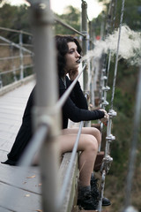 emo goth woman smoking overlooking from a bridge