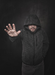Fototapeta na wymiar Unknown man in hood pointing by hand on dark. Focus on hand