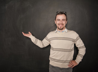 Smiling happy teacher with welcome gesture on blackboard