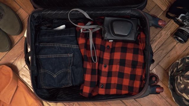 Man hands are fast packing suitcase for a journey. Man dreams about travell. Summer clothing, pasport with money and diving mask with snorkel. Top view