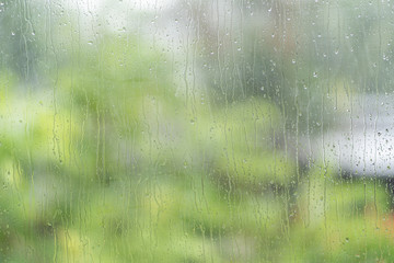 Raindrop on window with blur green tree background