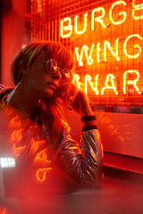 Portrait of woman with silver jacket and sunglasses in neon lights