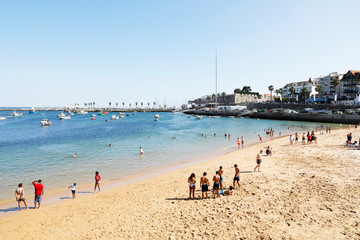 Obraz premium Cascais, Lisbon, Portugal - June 28, 2019: Tourists enjoy Ribeira Beach or Fisherman's Beach, in the center of Cascais, in Lisbon District, in Portugal.