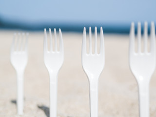 Close-up of plastic forks stuck in sand on the beach