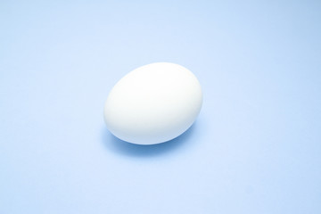 Fototapeta na wymiar White easter egg on blue background in center. Design, visual art, minimalism