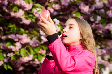 Obraz premium Natural cosmetics for skin. Girl in cherry flower. Kid with lipstick makeup. Small girl child in spring flower bloom. Smell of tender bloom. Sakura flower concept. Gorgeous flower and female beauty