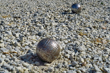 Gros plan sur boules de pétanque en acier sur sol de gravier.