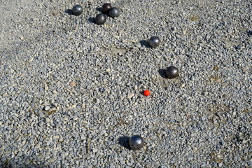 Parie de pétanque. Boules d'acier sur gravier. Cochonnet rouge. 