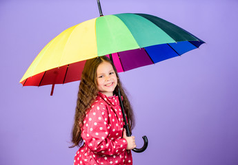 Rainy day fun. Happy walk under umbrella. Kid girl happy hold colorful rainbow umbrella. Rainy weather with proper garments. Bright umbrella. Enjoy rain concept. Be rainbow in someones cloud