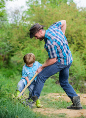 Fototapeta premium happy earth day. Dig grounf with shovel. new life. soils and fertilizers. rich natural soil. Eco farm. Ranch. small boy child help father in farming. father and son planting family tree. Care of soil