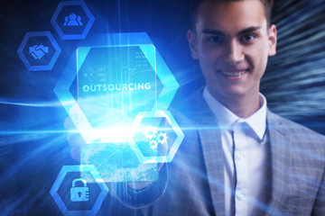The concept of business, technology, the Internet and the network. A young entrepreneur working on a virtual screen of the future and sees the inscription: Outsourcing