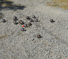 Parie de pétanque. Boules d'acier sur gravier. Cochonnet rouge. 