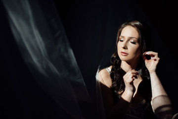 Beautiful bride on black background.Closeup portrait of young gorgeous bride. Close up eyes. Girl corrects hair. Studio shot. Beautiful bride portrait with veil near her face