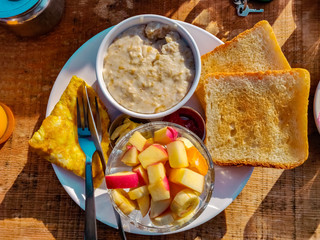 Morning breakfast. Toast, porridge, omelette and fruits served in a plate. Top view