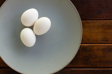 Chicken eggs on a plate and a wooden table.