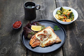 Fish and vegetables baked with tomatoes and cheese