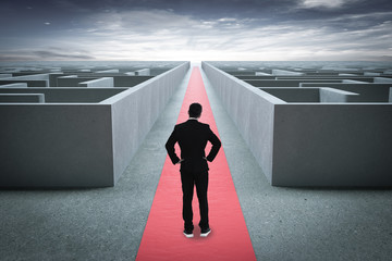 Businessman going straight ahead on a wide road between mazes
