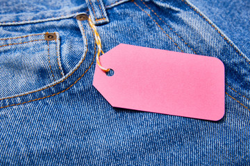 close up view of pink paper sale tag on rope on jeans